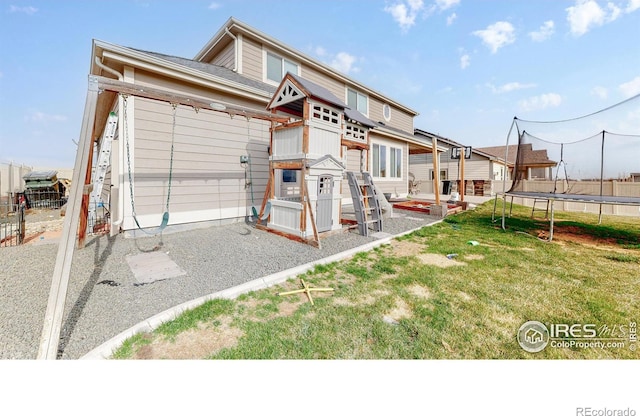 rear view of property with a yard and a trampoline