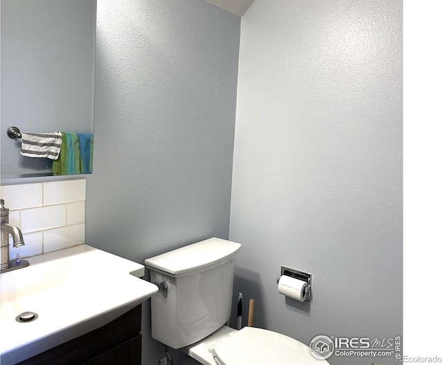 bathroom featuring decorative backsplash, toilet, and vanity