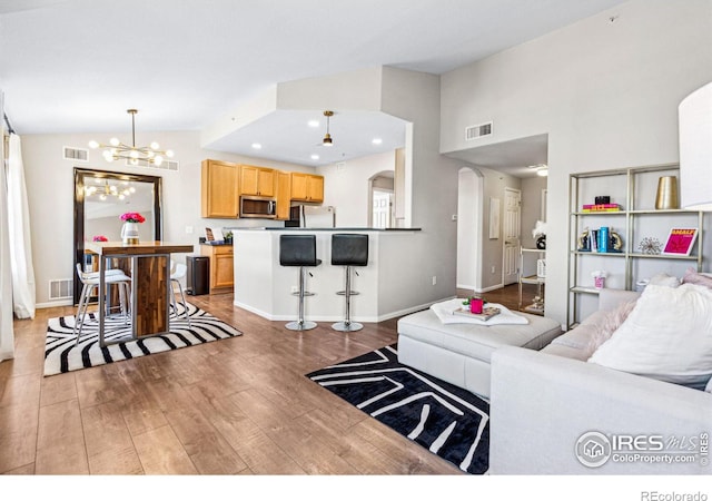 living room with an inviting chandelier, high vaulted ceiling, and hardwood / wood-style floors