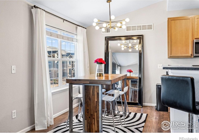 dining room featuring an inviting chandelier, dark hardwood / wood-style floors, and vaulted ceiling