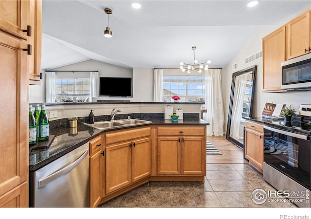 kitchen featuring vaulted ceiling, appliances with stainless steel finishes, sink, hanging light fixtures, and a notable chandelier