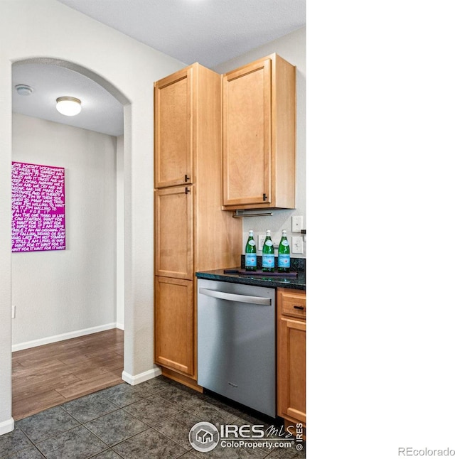 kitchen with stainless steel dishwasher, dark tile patterned flooring, and light brown cabinetry