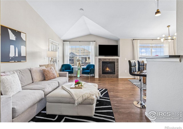 living room featuring a fireplace, vaulted ceiling, a chandelier, and wood-type flooring