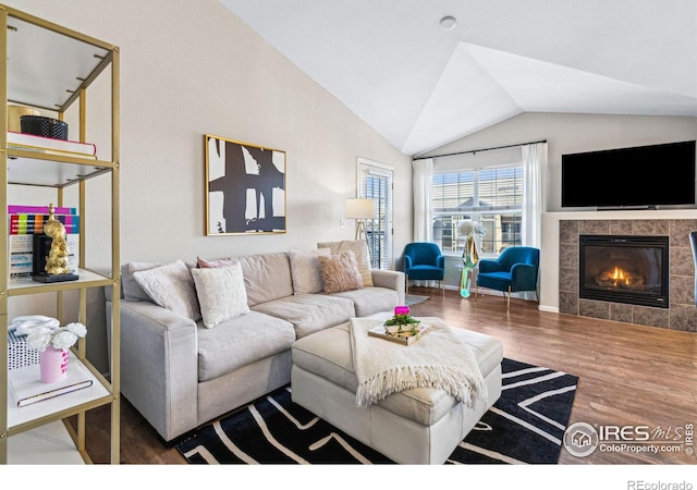 living room featuring lofted ceiling, a tiled fireplace, and hardwood / wood-style floors