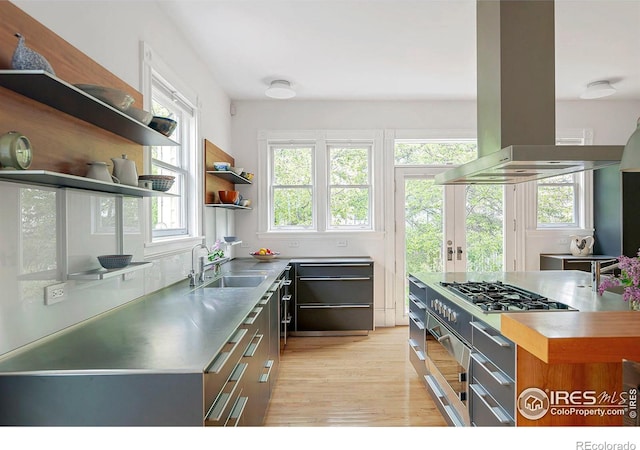 kitchen with stainless steel gas stovetop, sink, light hardwood / wood-style floors, stainless steel counters, and island range hood