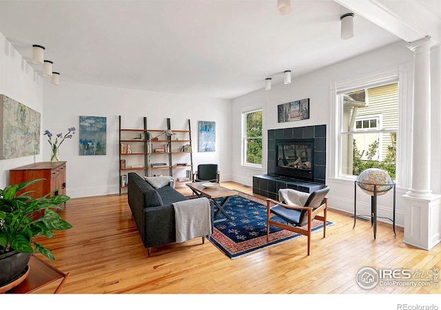 living room featuring a fireplace, light hardwood / wood-style flooring, and ornate columns