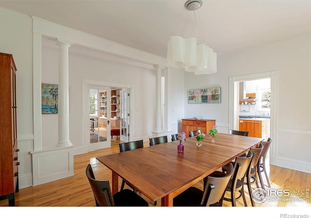 dining space featuring decorative columns, light hardwood / wood-style flooring, and plenty of natural light