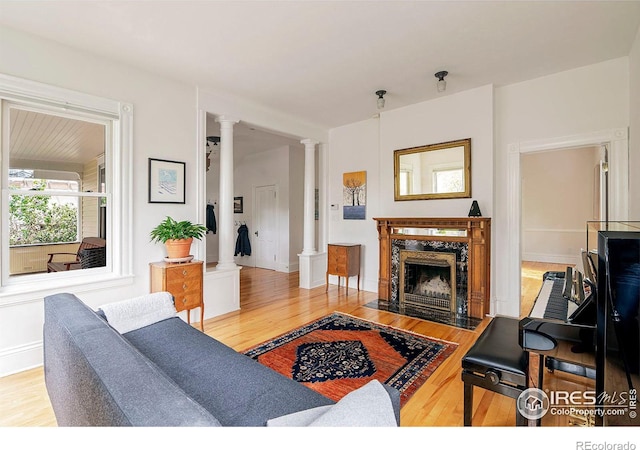 living room with a premium fireplace, hardwood / wood-style flooring, and ornate columns