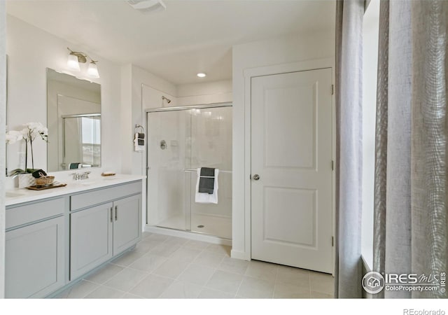 bathroom with tile patterned floors, a shower with door, and vanity