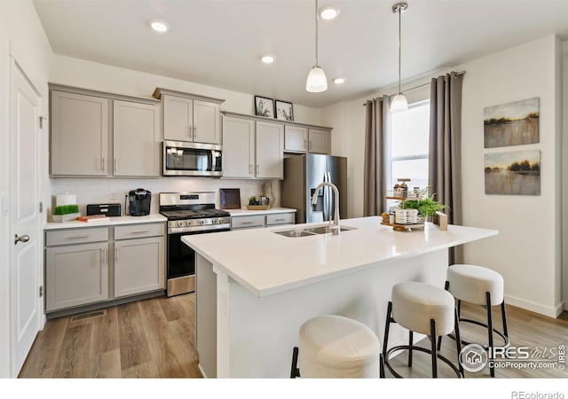 kitchen featuring a kitchen breakfast bar, pendant lighting, gray cabinetry, decorative backsplash, and stainless steel appliances