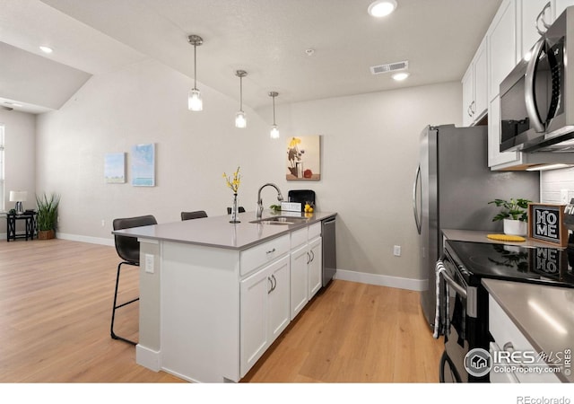 kitchen featuring appliances with stainless steel finishes, pendant lighting, sink, a kitchen bar, and kitchen peninsula