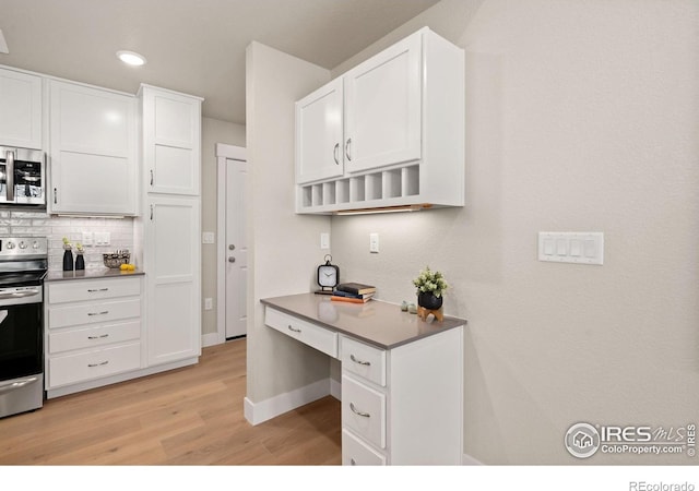 kitchen with stainless steel appliances, tasteful backsplash, white cabinets, and light hardwood / wood-style flooring