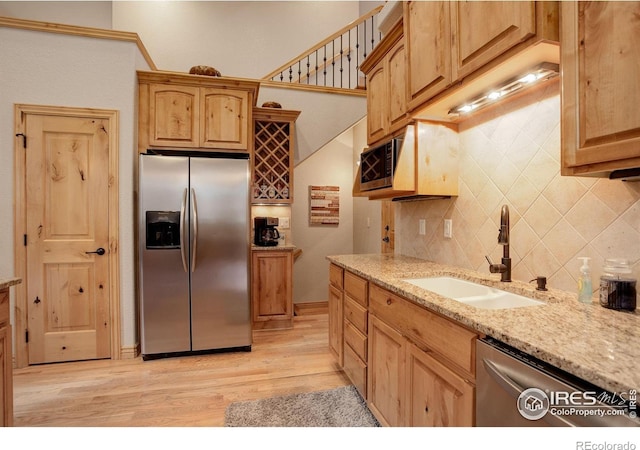 kitchen featuring tasteful backsplash, sink, light hardwood / wood-style flooring, stainless steel appliances, and light stone counters