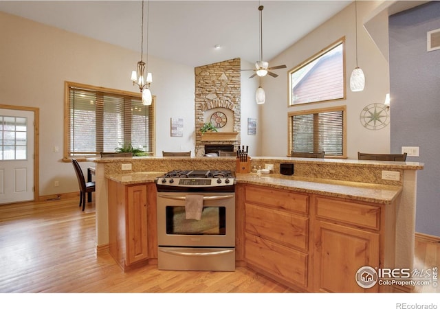 kitchen featuring a fireplace, light wood-type flooring, pendant lighting, and gas range