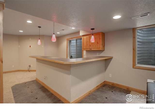 kitchen featuring kitchen peninsula, carpet flooring, pendant lighting, and a textured ceiling