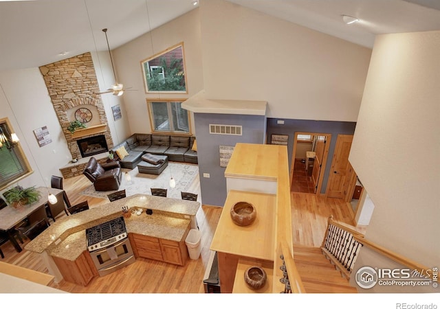 living room with a fireplace, light hardwood / wood-style floors, high vaulted ceiling, and ceiling fan