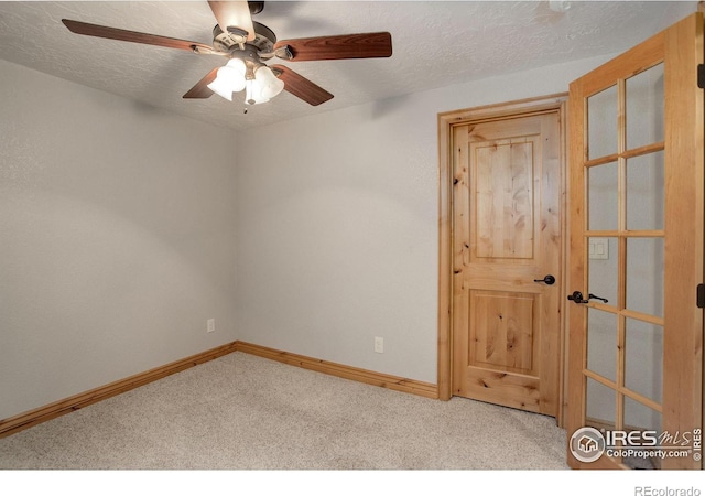 unfurnished room featuring ceiling fan, light colored carpet, and a textured ceiling