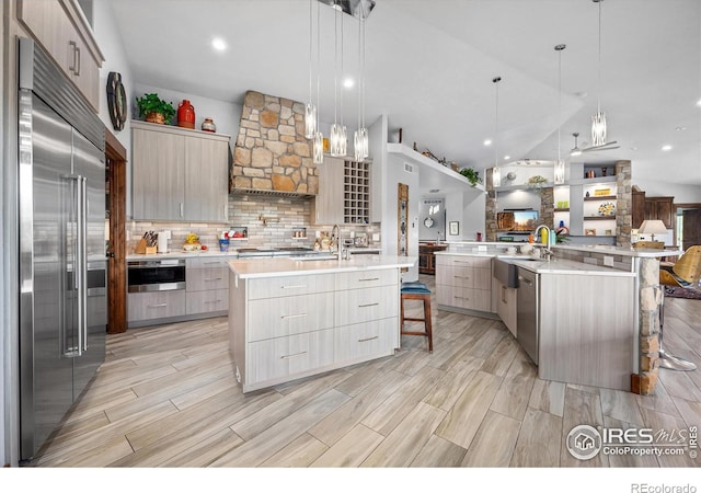 kitchen with appliances with stainless steel finishes, tasteful backsplash, a large island, a kitchen breakfast bar, and decorative light fixtures