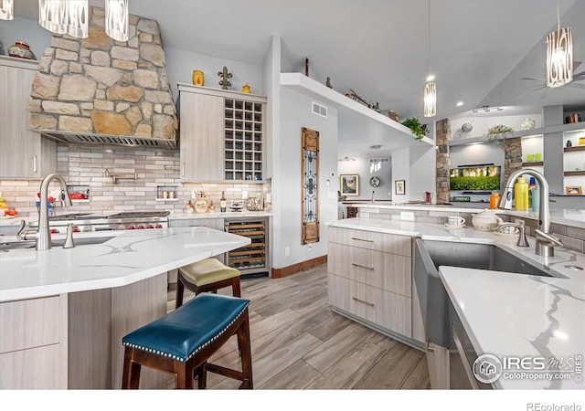 kitchen featuring decorative light fixtures, decorative backsplash, a breakfast bar area, and wine cooler