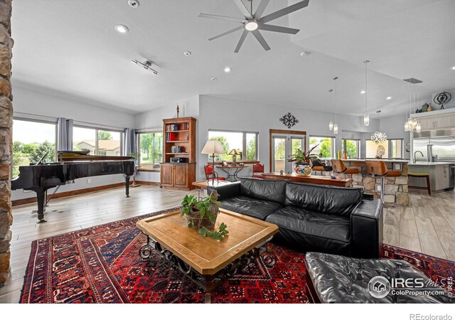 living room with sink, light hardwood / wood-style flooring, and lofted ceiling