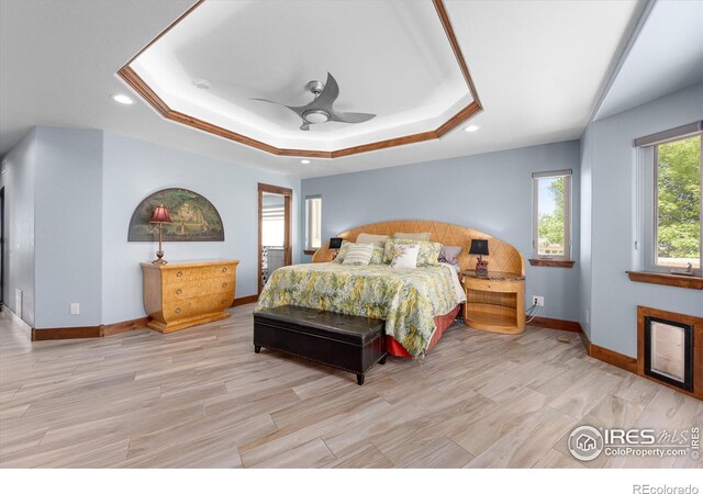 bedroom featuring ceiling fan, light hardwood / wood-style flooring, and a raised ceiling