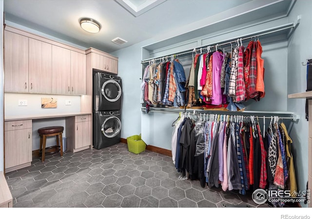 laundry room with cabinets and stacked washer and clothes dryer