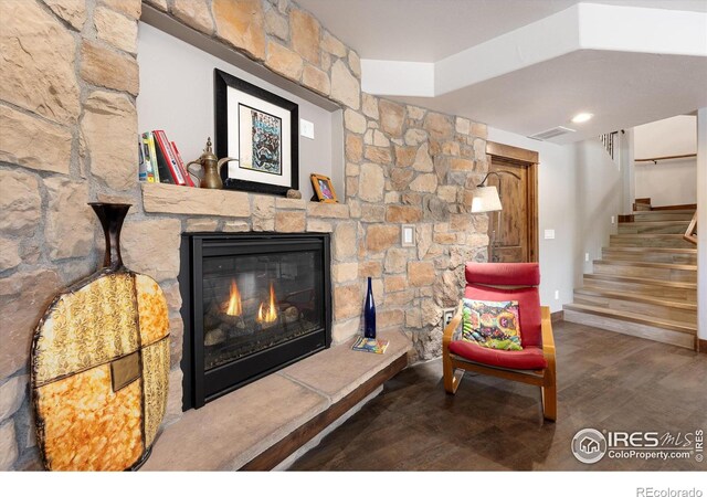 living room featuring a stone fireplace and wood-type flooring