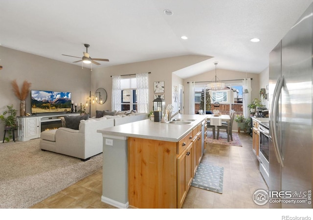 kitchen featuring a wealth of natural light, an island with sink, freestanding refrigerator, and light colored carpet