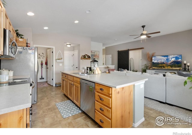 kitchen with a barn door, stainless steel appliances, light countertops, and open floor plan