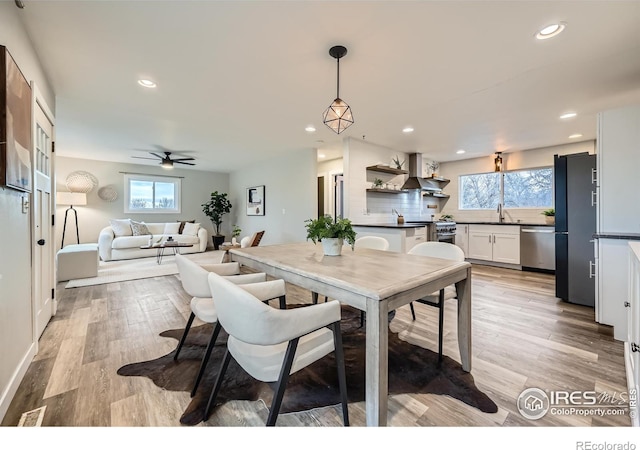 dining room featuring ceiling fan, sink, and light wood-type flooring