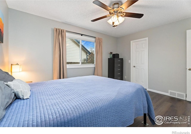 bedroom with ceiling fan, dark wood-type flooring, and a textured ceiling