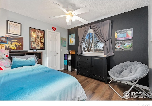 bedroom featuring ceiling fan, dark wood-type flooring, and a textured ceiling