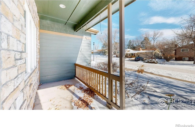 snow covered deck featuring covered porch