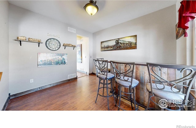 dining area with dark hardwood / wood-style floors and bar