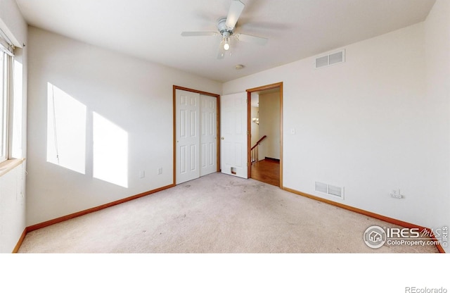 unfurnished bedroom featuring ceiling fan, a closet, and light carpet