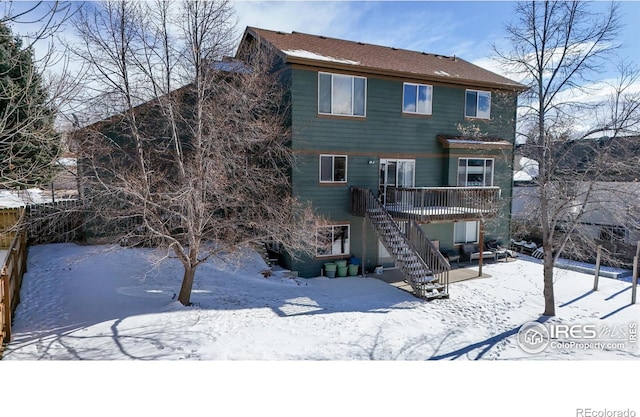 snow covered rear of property with a deck