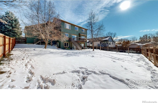 snow covered rear of property with a deck