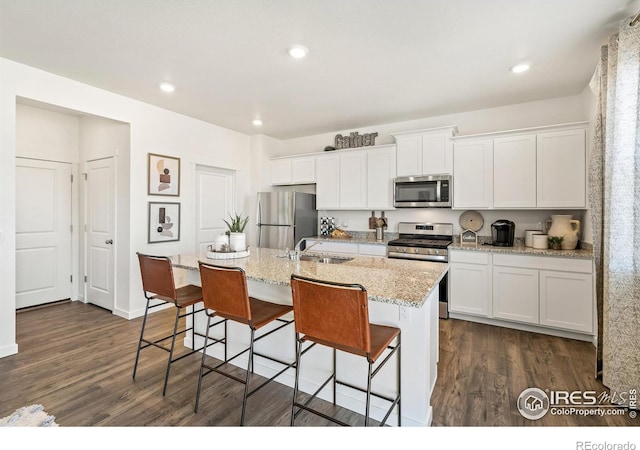 kitchen with dark hardwood / wood-style flooring, sink, white cabinetry, a center island with sink, and stainless steel appliances