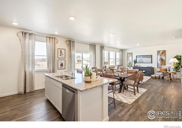 kitchen with white cabinets, sink, a kitchen island with sink, light stone counters, and stainless steel dishwasher