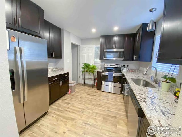 kitchen featuring sink, dark brown cabinets, decorative light fixtures, light hardwood / wood-style flooring, and stainless steel appliances