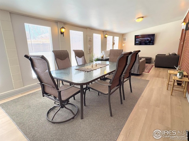 dining area with light wood-type flooring and lofted ceiling