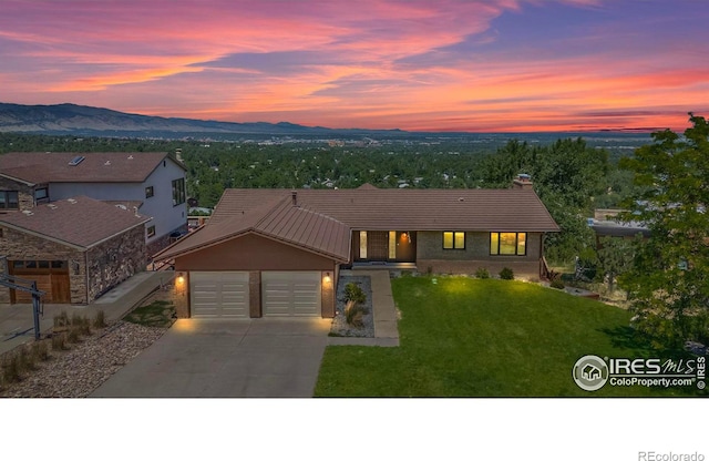 view of front of home with a mountain view, a lawn, and a garage