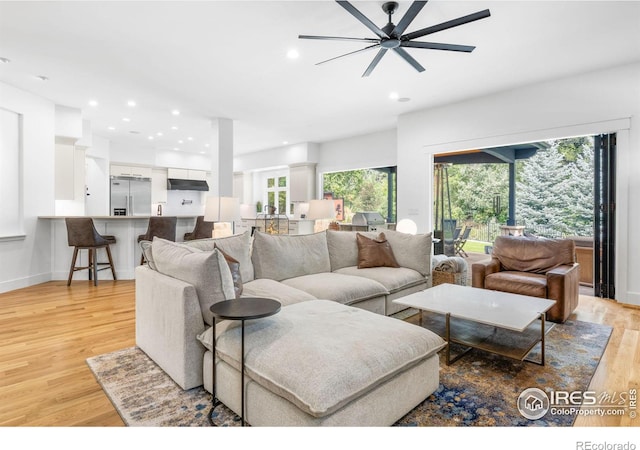 living room with ceiling fan, plenty of natural light, and light hardwood / wood-style flooring