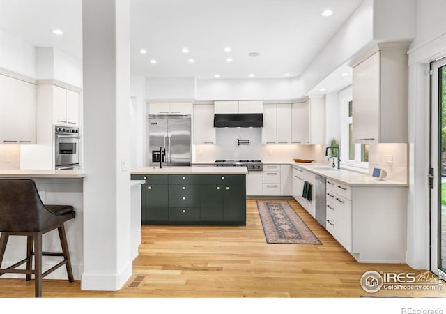 kitchen with plenty of natural light, white cabinetry, ventilation hood, and appliances with stainless steel finishes