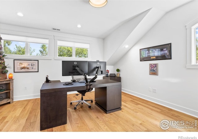 office with light wood-type flooring and lofted ceiling