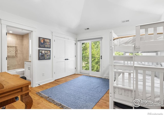 bedroom with light hardwood / wood-style flooring, ensuite bath, and access to outside