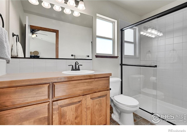 bathroom with vanity, backsplash, an enclosed shower, and toilet