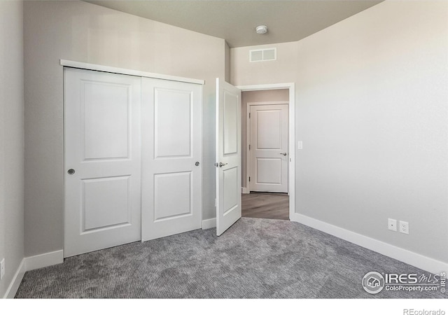 unfurnished bedroom featuring a closet and dark colored carpet