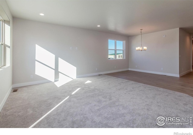 carpeted spare room featuring a notable chandelier