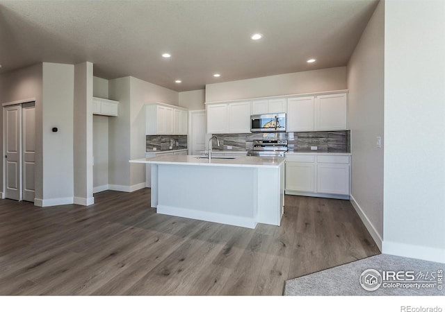 kitchen with tasteful backsplash, white cabinetry, appliances with stainless steel finishes, and an island with sink
